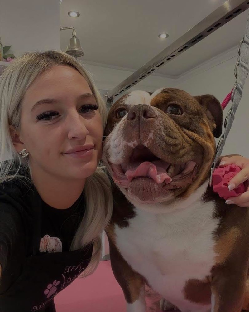 Charlotte cuddling a happy bulldog in the salon